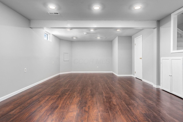 below grade area with dark wood-style floors, visible vents, and baseboards