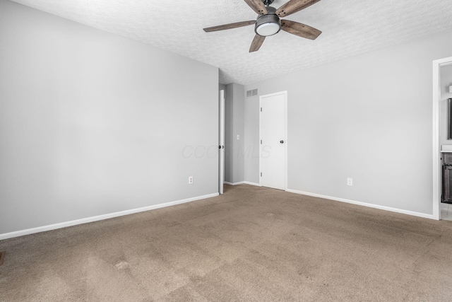 carpeted empty room featuring a ceiling fan, visible vents, a textured ceiling, and baseboards