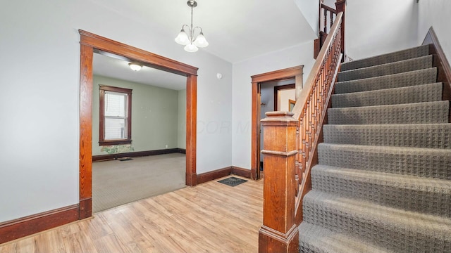 stairs with baseboards, a chandelier, and wood finished floors