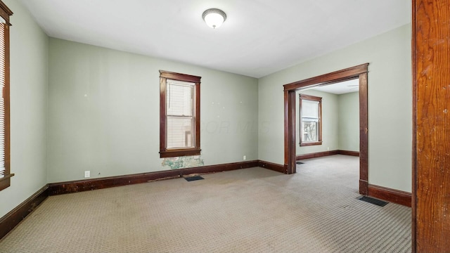 spare room featuring light carpet, visible vents, and baseboards