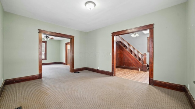 unfurnished room featuring light carpet, stairway, and baseboards