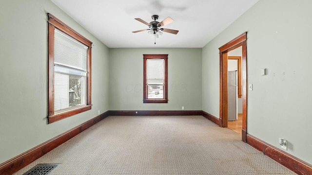 empty room with light carpet, baseboards, visible vents, and a ceiling fan