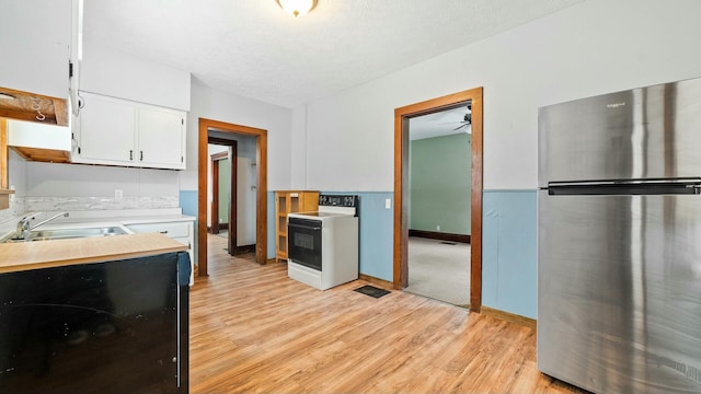 kitchen with white electric stove, light countertops, freestanding refrigerator, white cabinetry, and a sink