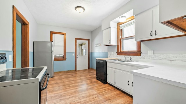 kitchen featuring white cabinets, freestanding refrigerator, light countertops, white electric range, and a sink