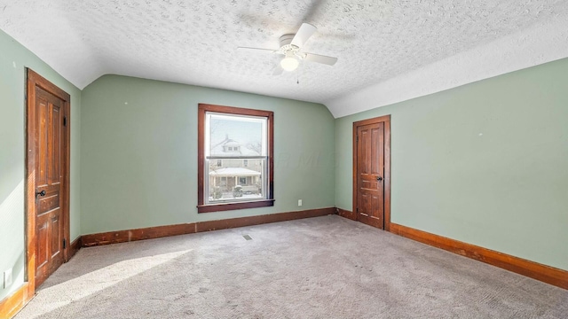 spare room featuring lofted ceiling, ceiling fan, a textured ceiling, baseboards, and carpet