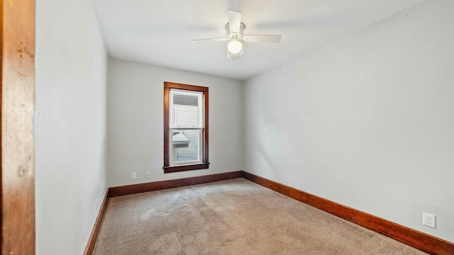 carpeted spare room featuring a ceiling fan and baseboards