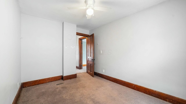 spare room featuring a ceiling fan, visible vents, light carpet, and baseboards