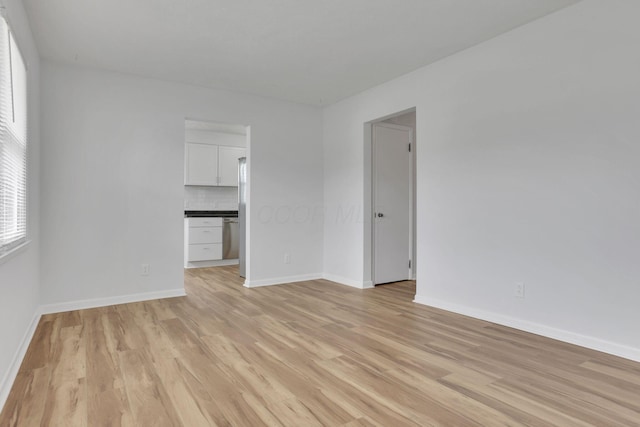 unfurnished room with light wood-style flooring and baseboards