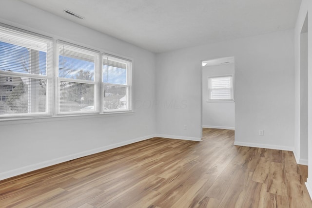 spare room featuring light wood-style floors, visible vents, and baseboards