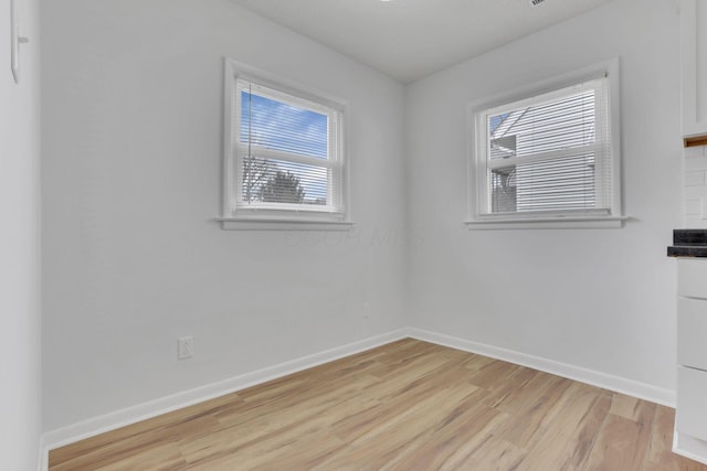 unfurnished room with light wood finished floors and baseboards