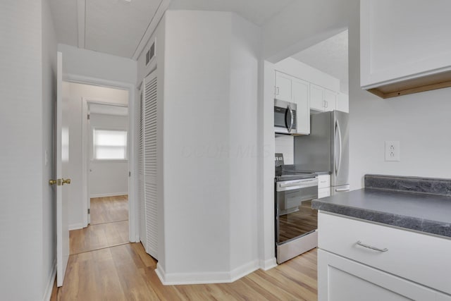 kitchen featuring dark countertops, visible vents, appliances with stainless steel finishes, light wood-style floors, and white cabinetry