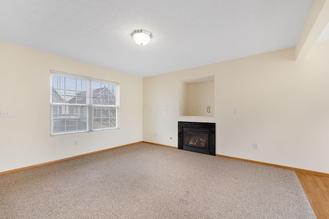 unfurnished living room featuring light carpet, a fireplace, a textured ceiling, and baseboards