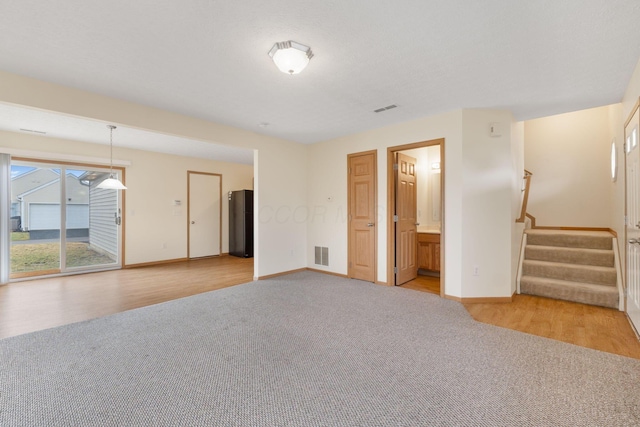 spare room featuring light carpet, stairway, visible vents, and baseboards