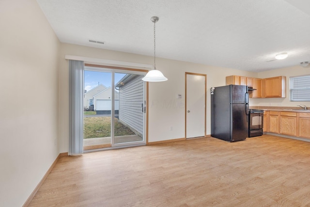 kitchen with black appliances, light wood finished floors, a sink, and visible vents