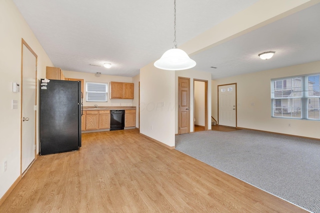 kitchen featuring light countertops, hanging light fixtures, light wood-style floors, black appliances, and baseboards