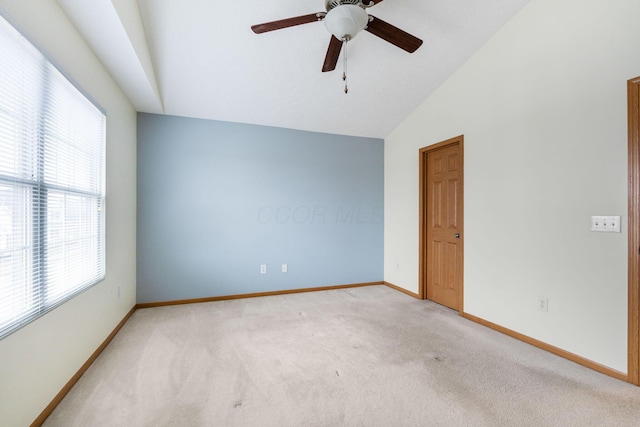 spare room featuring vaulted ceiling, light carpet, a ceiling fan, and baseboards