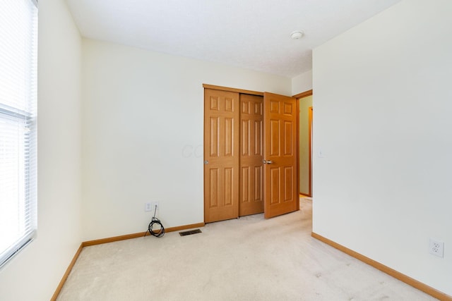 carpeted empty room with baseboards, visible vents, and a healthy amount of sunlight