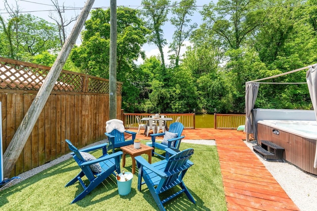 view of yard featuring outdoor dining space, fence, a wooden deck, and a hot tub