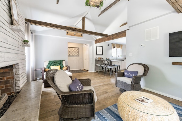 living area with beam ceiling, wood finished floors, and visible vents