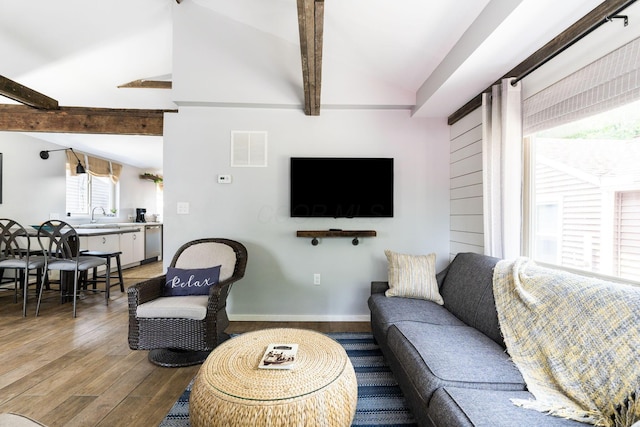 living room featuring lofted ceiling with beams, wood finished floors, visible vents, and baseboards