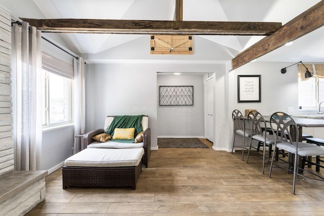 living area with lofted ceiling with beams, baseboards, and wood finished floors