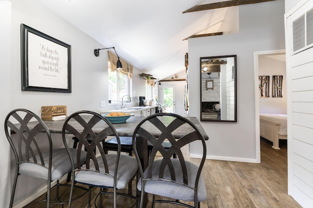 dining area featuring vaulted ceiling with beams, baseboards, and wood finished floors