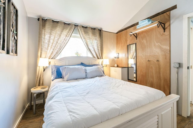 bedroom with vaulted ceiling, wood finished floors, and baseboards
