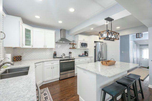 kitchen featuring pendant lighting, stainless steel appliances, glass insert cabinets, white cabinets, and wall chimney exhaust hood