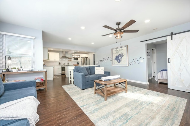 living area featuring ceiling fan, a barn door, dark wood finished floors, and recessed lighting