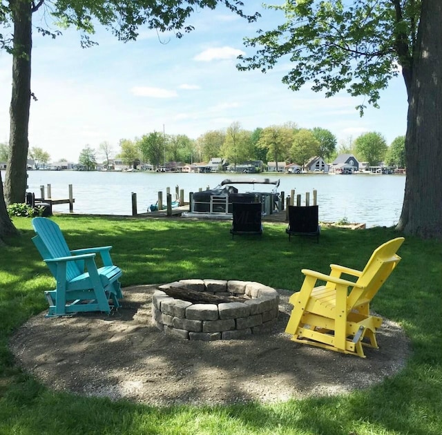 view of property's community featuring an outdoor fire pit, a lawn, and a water view