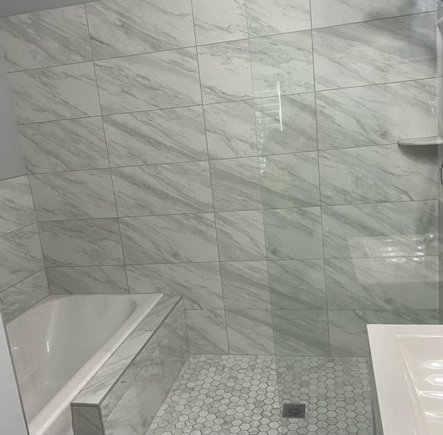 bathroom featuring a relaxing tiled tub and a tile shower