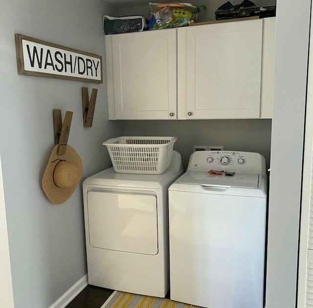 washroom with baseboards, wood finished floors, cabinet space, and washer and dryer