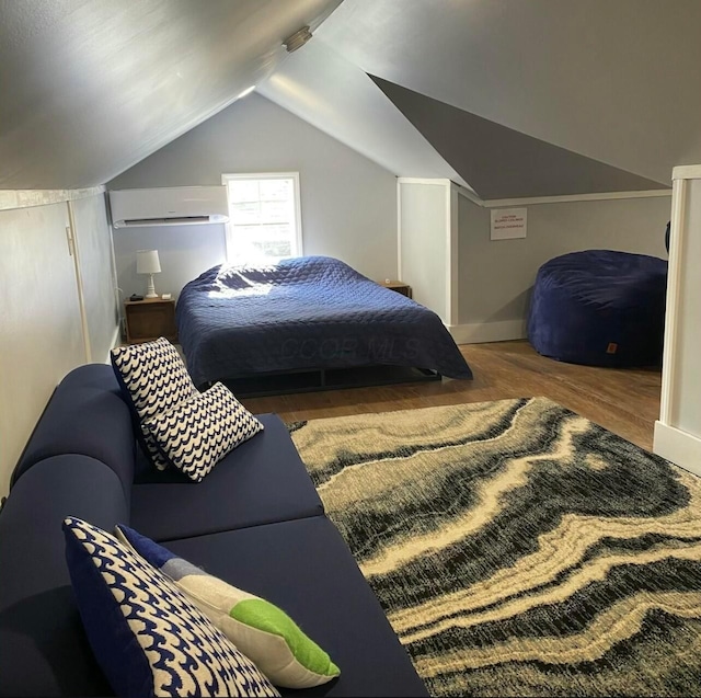 bedroom with lofted ceiling, a wall mounted air conditioner, wood finished floors, and baseboards