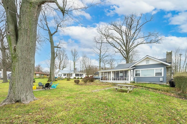 view of yard featuring a fire pit and a sunroom