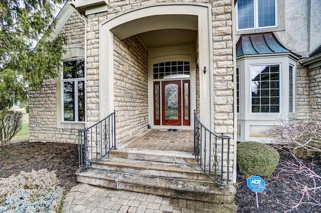 view of exterior entry with metal roof, a standing seam roof, and stone siding