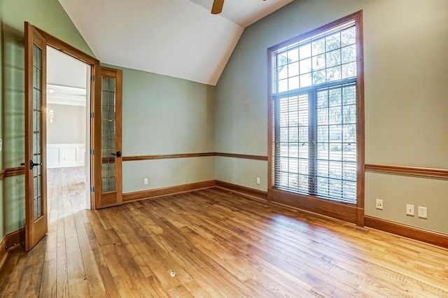 spare room with vaulted ceiling, baseboards, hardwood / wood-style flooring, and a ceiling fan