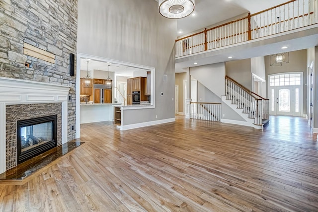 unfurnished living room featuring light wood-style floors, stairs, baseboards, and a fireplace