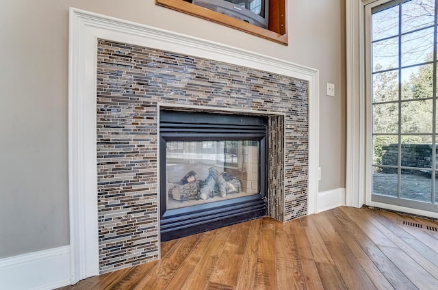 interior details with wood finished floors and a tile fireplace