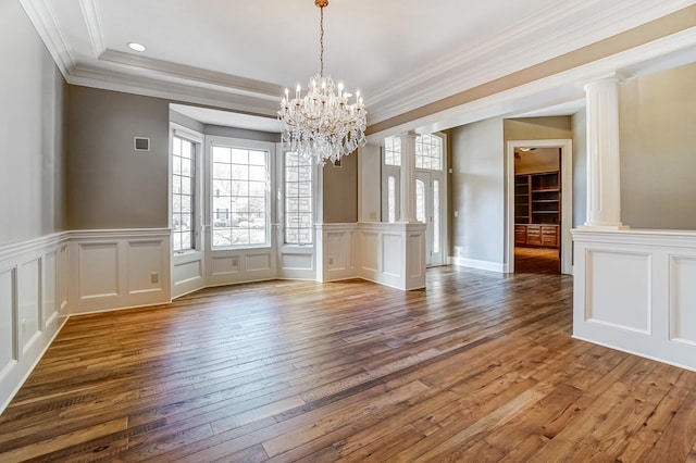 unfurnished dining area with visible vents, decorative columns, a decorative wall, and hardwood / wood-style floors