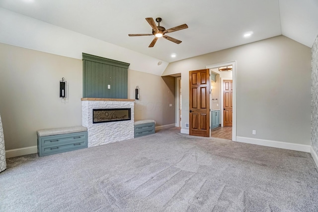 unfurnished living room with light carpet, a fireplace, lofted ceiling, and baseboards