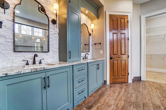 full bathroom with double vanity, wood finished floors, and a sink