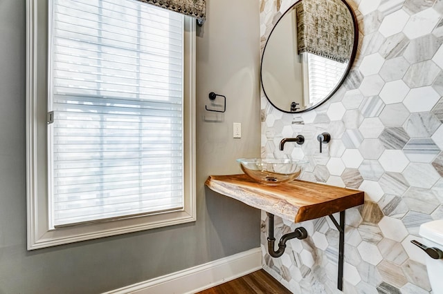 half bathroom with a sink, baseboards, and wood finished floors