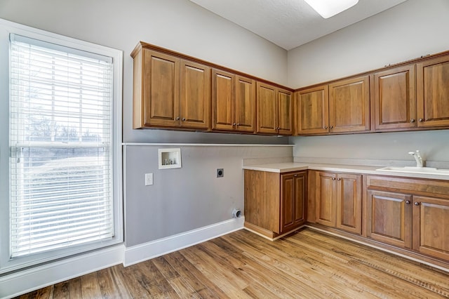 washroom featuring light wood finished floors, hookup for a washing machine, cabinet space, hookup for an electric dryer, and a sink