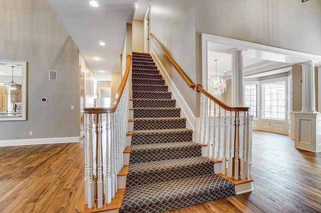 stairs with baseboards, hardwood / wood-style floors, and ornate columns