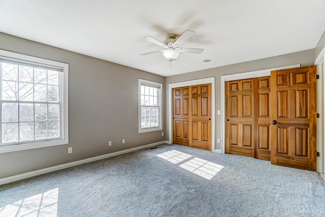 unfurnished bedroom with a ceiling fan, baseboards, two closets, and carpet flooring