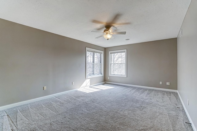 empty room featuring a textured ceiling, ceiling fan, carpet flooring, and baseboards