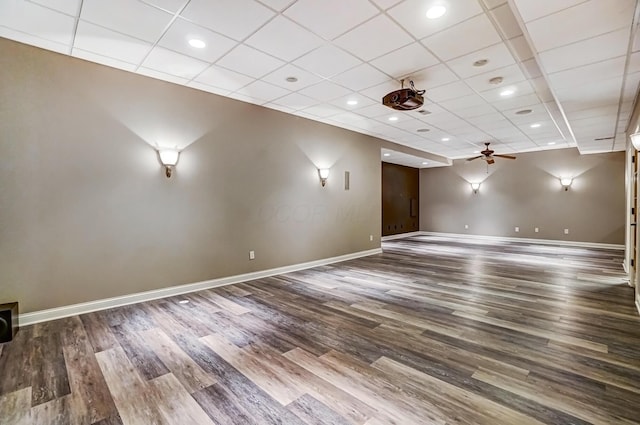 interior space with a paneled ceiling, wood finished floors, a ceiling fan, and baseboards