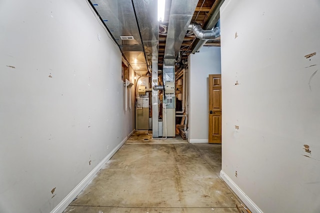 hallway featuring visible vents, concrete floors, and baseboards