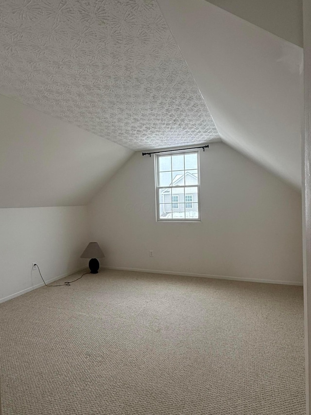 bonus room featuring carpet, vaulted ceiling, a textured ceiling, and baseboards