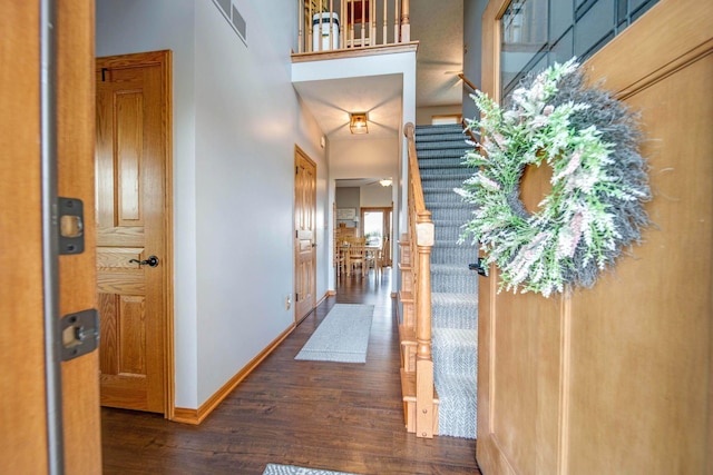 foyer entrance with dark wood-type flooring, visible vents, baseboards, and stairs